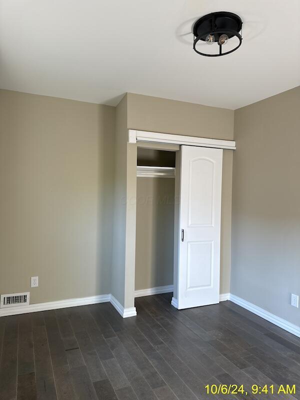 unfurnished bedroom with dark hardwood / wood-style floors and a closet