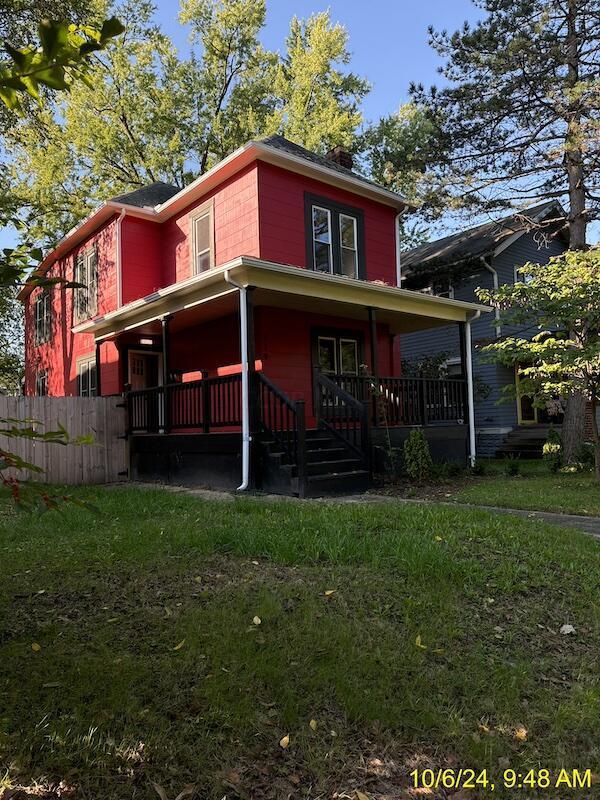 rear view of house with a porch and a lawn