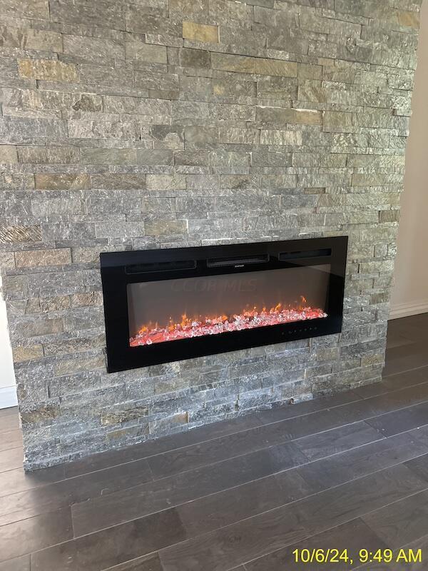 room details with hardwood / wood-style flooring and a stone fireplace