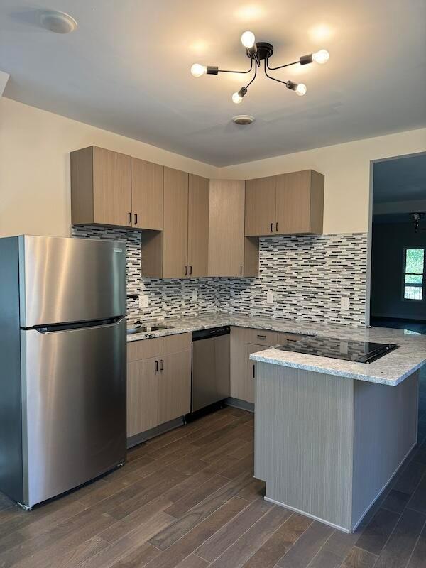 kitchen featuring kitchen peninsula, dark hardwood / wood-style flooring, light stone counters, stainless steel appliances, and light brown cabinets