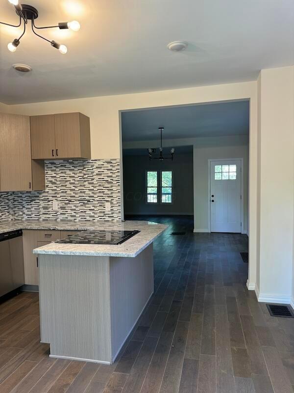 kitchen featuring light brown cabinets, dark wood-type flooring, stainless steel dishwasher, a notable chandelier, and black electric cooktop