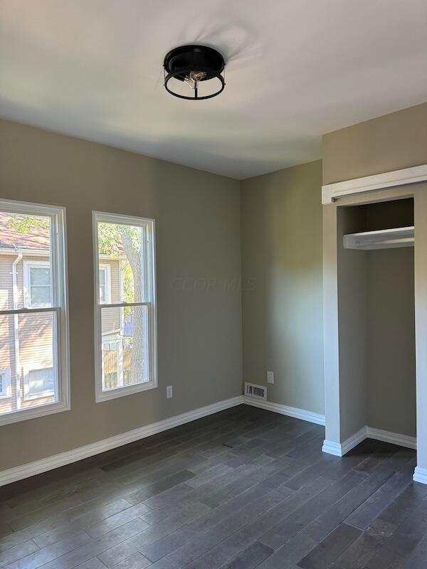 unfurnished bedroom featuring a closet and dark hardwood / wood-style flooring