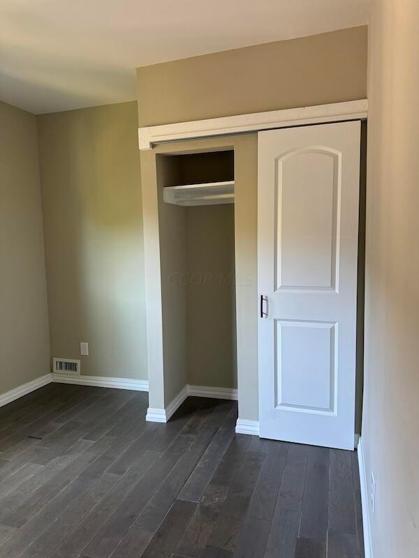 unfurnished bedroom featuring dark wood-type flooring and a closet