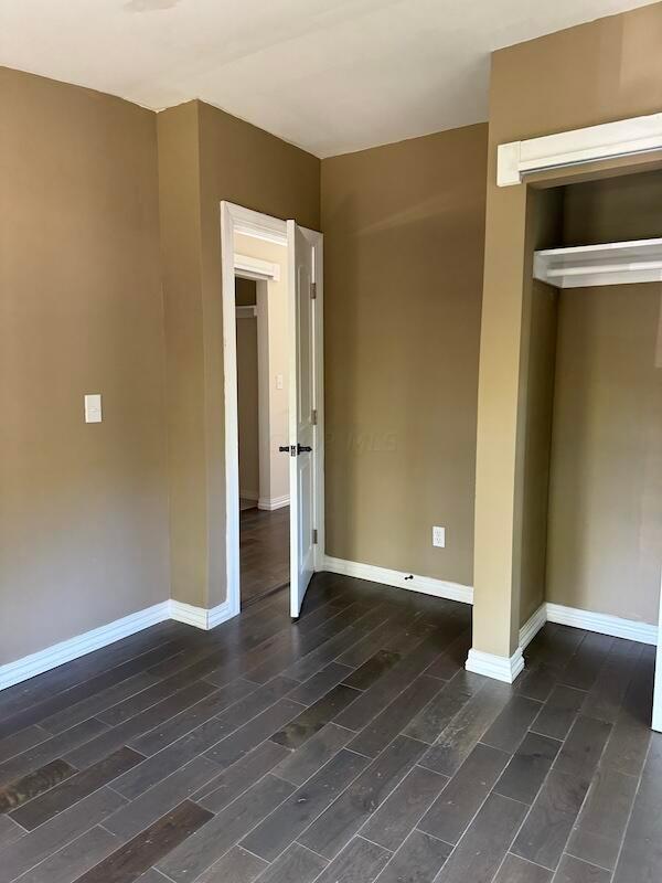 unfurnished bedroom featuring dark hardwood / wood-style floors and a closet