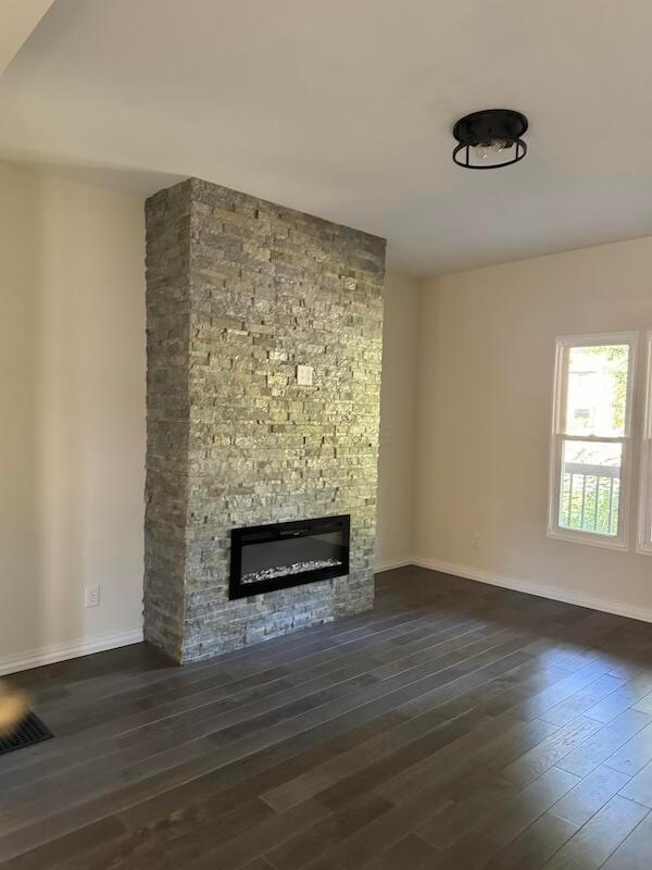 unfurnished living room with a fireplace and dark wood-type flooring