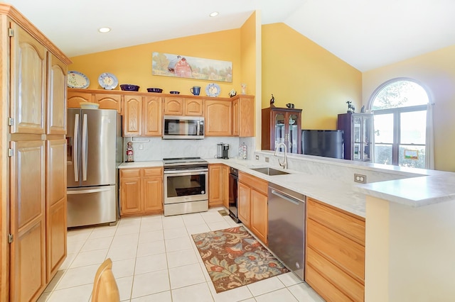 kitchen featuring sink, vaulted ceiling, tasteful backsplash, kitchen peninsula, and stainless steel appliances