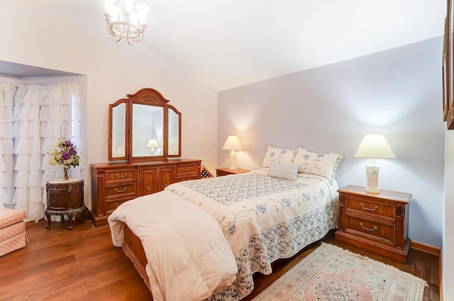 bedroom featuring hardwood / wood-style floors, lofted ceiling, and a notable chandelier