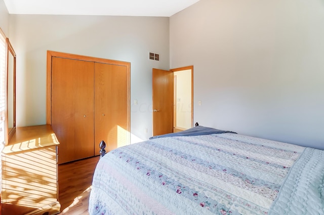 bedroom with a closet, high vaulted ceiling, and light hardwood / wood-style flooring