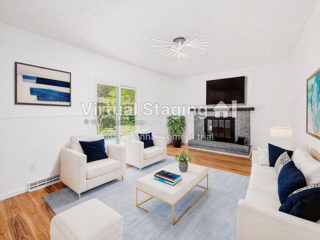 living room with a chandelier, hardwood / wood-style flooring, and a brick fireplace