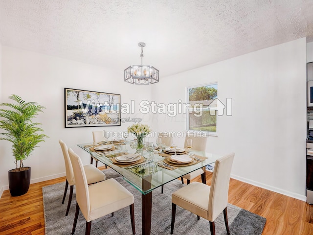 dining space featuring a chandelier, wood-type flooring, and a textured ceiling