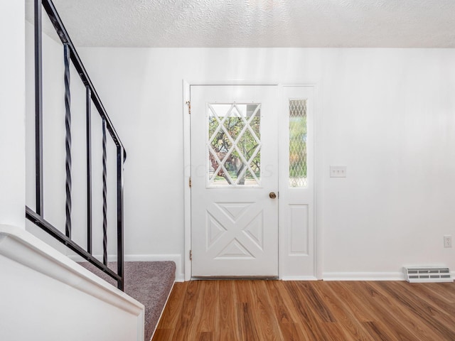 foyer with wood-type flooring and a textured ceiling