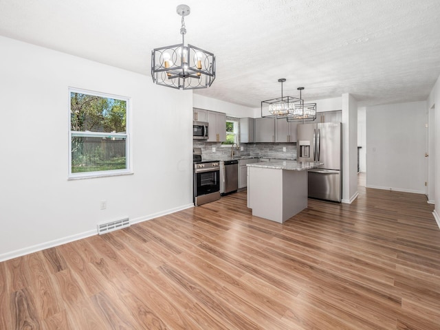 kitchen with gray cabinets, a wealth of natural light, a center island, and appliances with stainless steel finishes