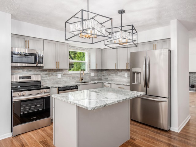 kitchen with sink, a center island, light hardwood / wood-style floors, gray cabinets, and appliances with stainless steel finishes