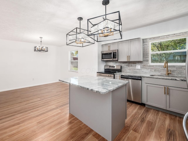 kitchen featuring appliances with stainless steel finishes, sink, pendant lighting, gray cabinets, and plenty of natural light