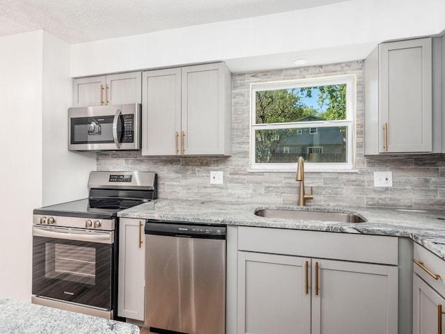 kitchen with gray cabinets, light stone countertops, sink, and stainless steel appliances