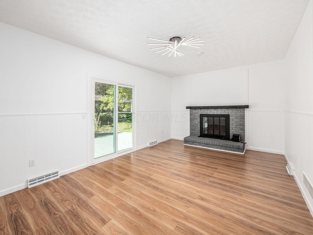 unfurnished living room featuring hardwood / wood-style floors, a fireplace, and a textured ceiling