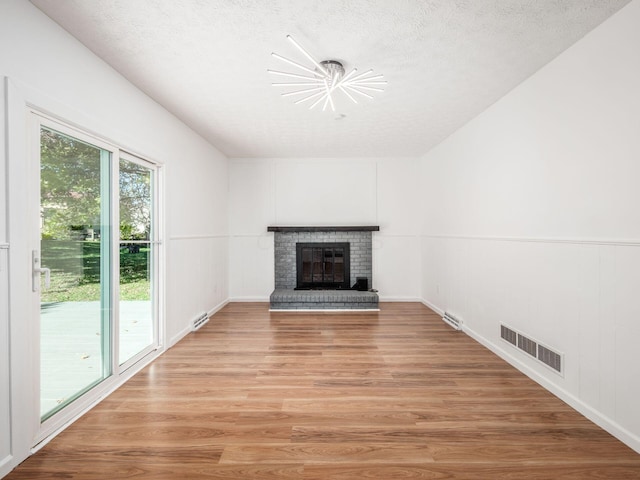 unfurnished living room with a fireplace, a textured ceiling, and hardwood / wood-style flooring