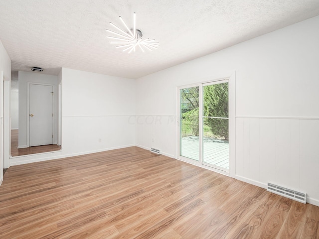 unfurnished room featuring a textured ceiling and light wood-type flooring