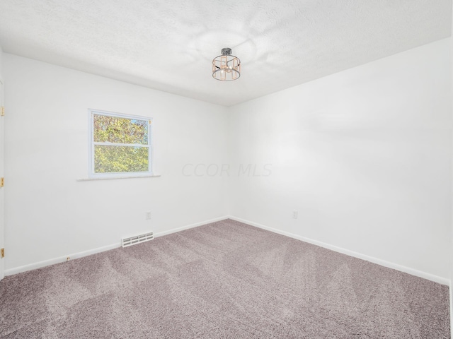 carpeted empty room featuring a textured ceiling