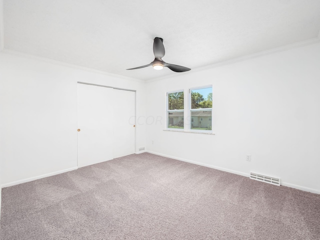 carpeted empty room featuring ceiling fan and crown molding