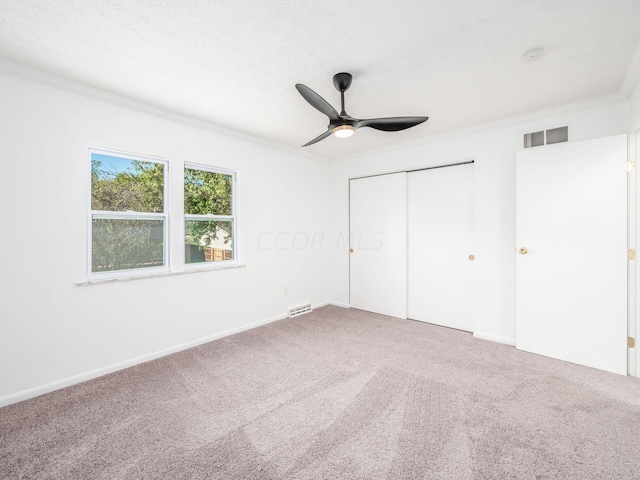 unfurnished bedroom featuring ceiling fan, carpet floors, crown molding, and a closet