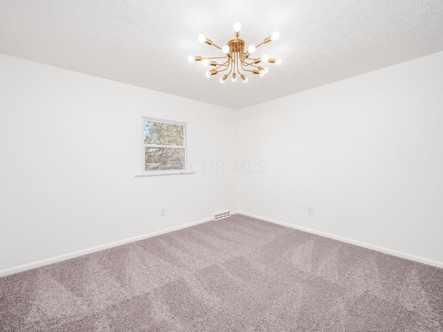 empty room with carpet flooring, a chandelier, and a textured ceiling