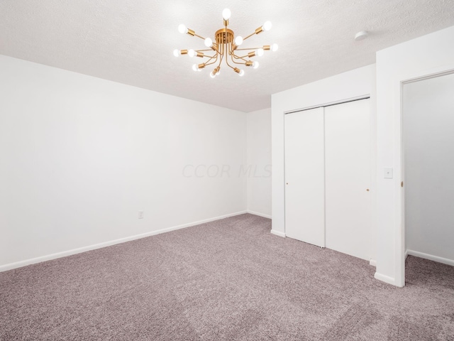 unfurnished bedroom with carpet, a notable chandelier, a textured ceiling, and a closet