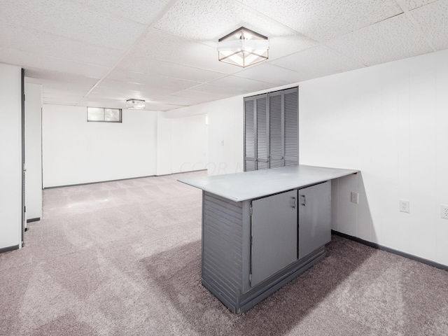 basement featuring a drop ceiling and dark carpet