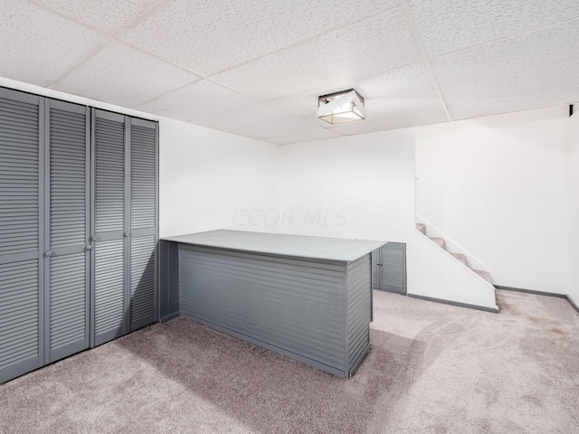 interior space featuring a drop ceiling and light colored carpet