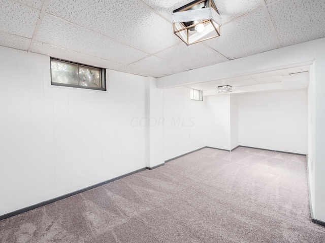 basement featuring light carpet and a paneled ceiling