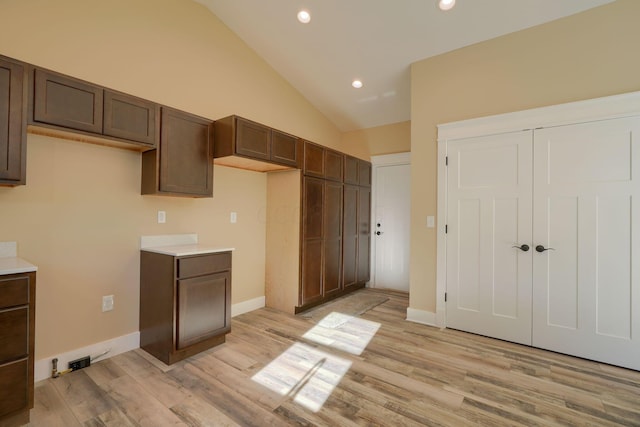 kitchen featuring dark brown cabinetry, high vaulted ceiling, and light hardwood / wood-style flooring