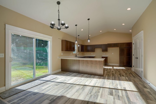 kitchen featuring kitchen peninsula, sink, a chandelier, light hardwood / wood-style floors, and lofted ceiling