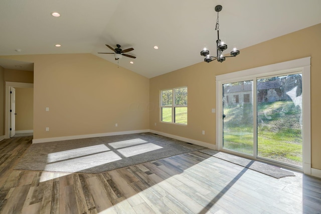 spare room featuring ceiling fan with notable chandelier, light hardwood / wood-style floors, and lofted ceiling