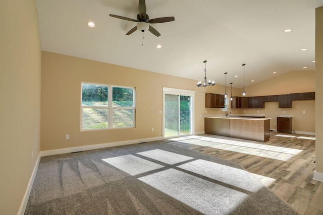 unfurnished living room featuring sink, ceiling fan with notable chandelier, lofted ceiling, and light wood-type flooring