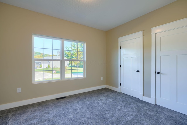 unfurnished bedroom with dark carpet