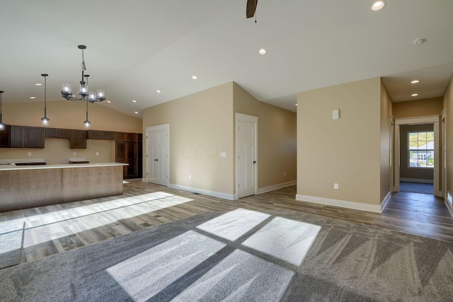 unfurnished living room with ceiling fan with notable chandelier, light hardwood / wood-style floors, and lofted ceiling