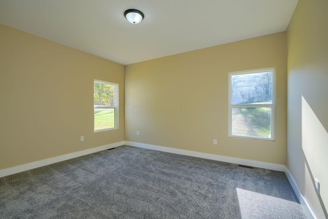 spare room featuring dark colored carpet