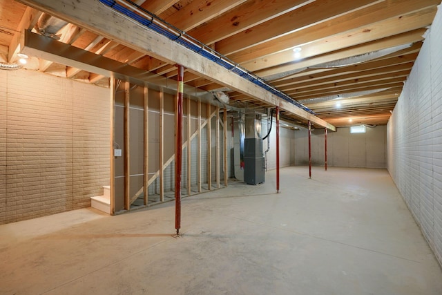 basement featuring brick wall and heating unit