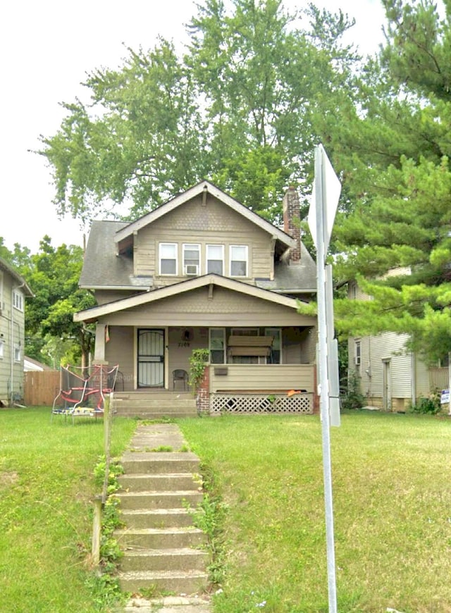 view of front facade with covered porch, a trampoline, and a front lawn