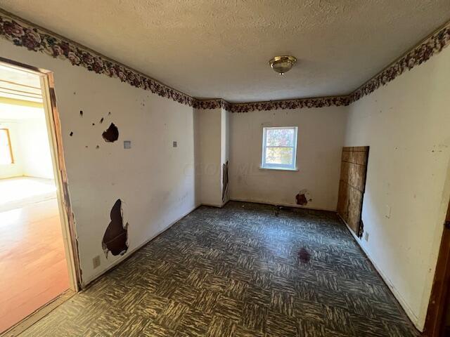 spare room with dark parquet flooring and a textured ceiling