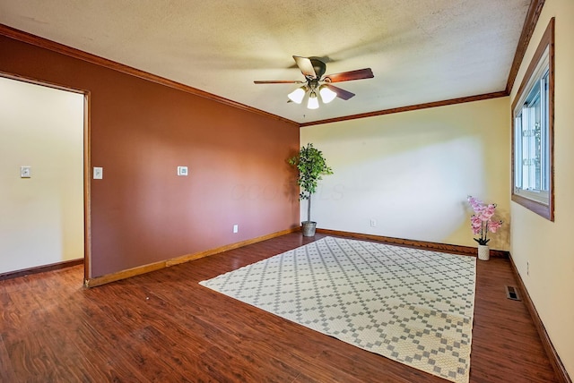 empty room with a textured ceiling, ceiling fan, ornamental molding, and dark wood-type flooring