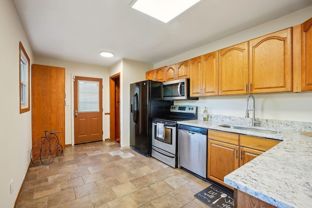 kitchen featuring light stone countertops, sink, and stainless steel appliances