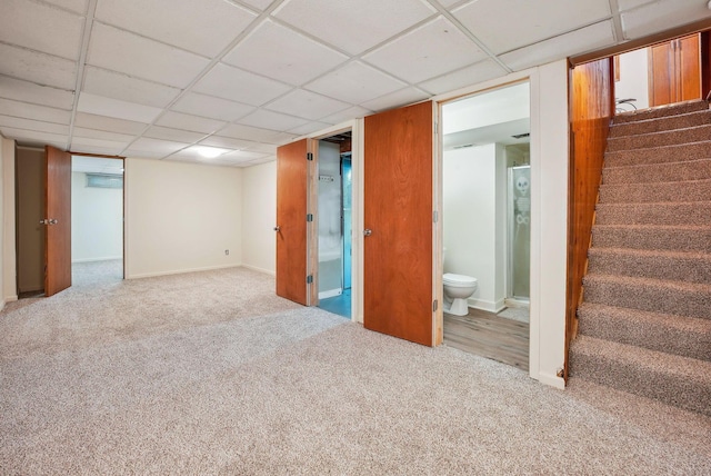 basement with a paneled ceiling and light colored carpet