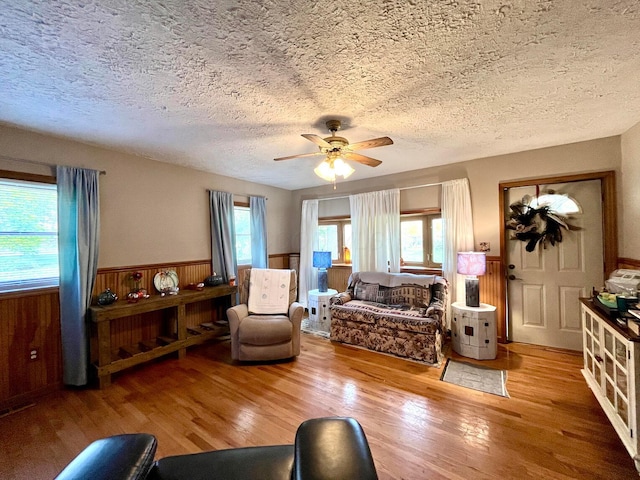 living room featuring ceiling fan, hardwood / wood-style floors, a healthy amount of sunlight, and a textured ceiling