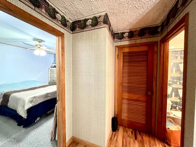 bedroom featuring ceiling fan, light hardwood / wood-style floors, and a textured ceiling