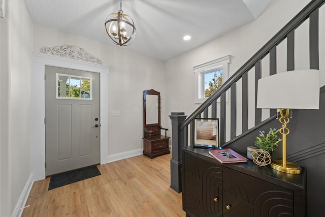 foyer entrance featuring light hardwood / wood-style flooring, a chandelier, and vaulted ceiling