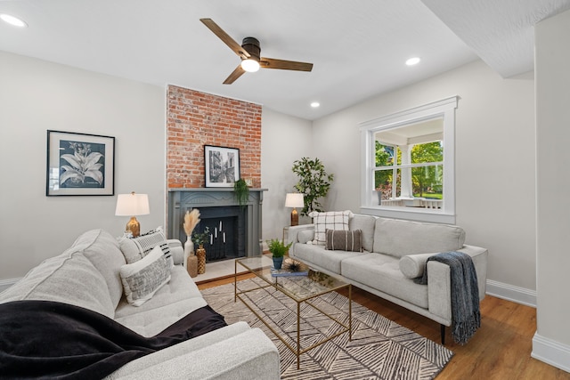 living room with ceiling fan, a fireplace, and light hardwood / wood-style flooring