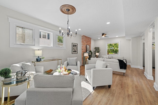 living room with light hardwood / wood-style flooring and ceiling fan with notable chandelier