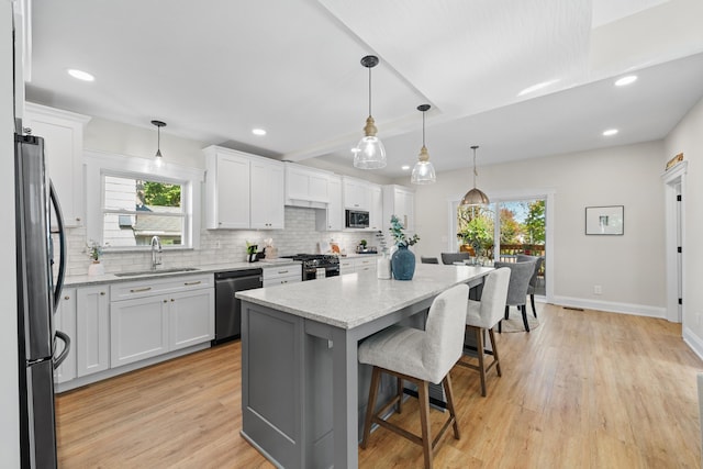 kitchen featuring white cabinets, a center island, stainless steel appliances, and sink