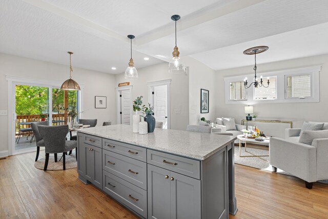 kitchen with pendant lighting, light hardwood / wood-style floors, and light stone counters